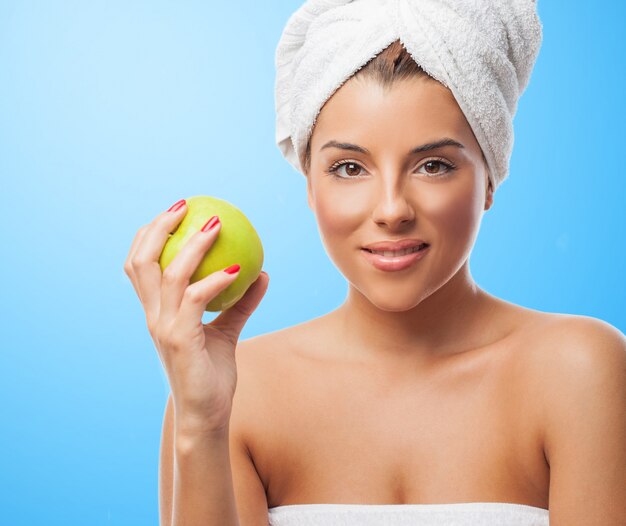Glimlachende vrouw in witte handdoek met appel