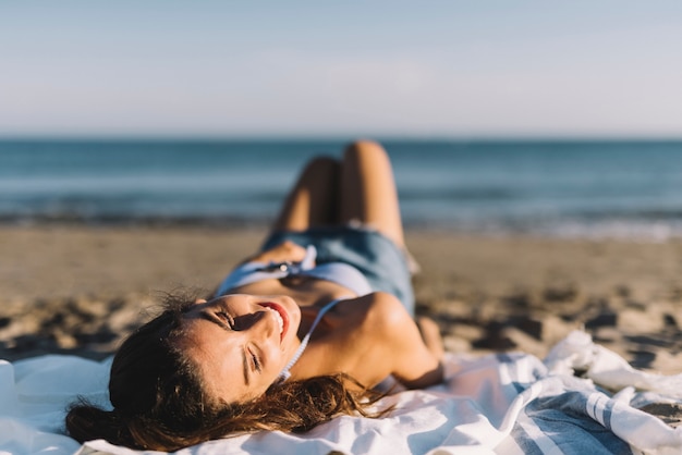 Glimlachende vrouw liggend op het strand