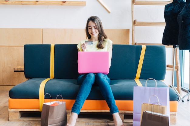 Glimlachende vrouw met creditcard die laptop met behulp van