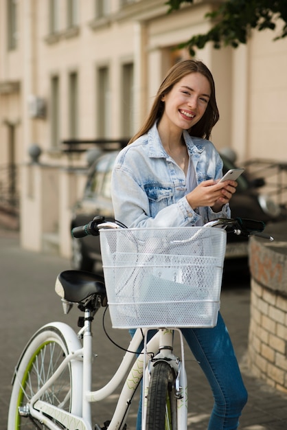 Gratis foto glimlachende vrouw naast haar fiets