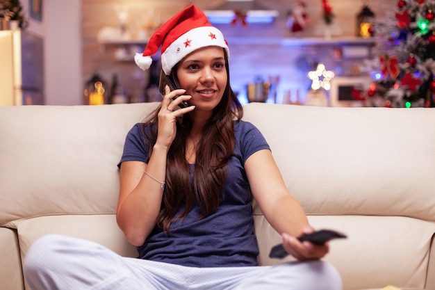 Glimlachende vrouw praten met vriend aan de telefoon kijken naar kerstfilm ontspannen