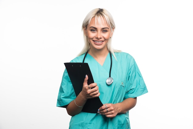 Glimlachende vrouwelijke arts die een klembord op witte achtergrond houdt. Hoge kwaliteit foto