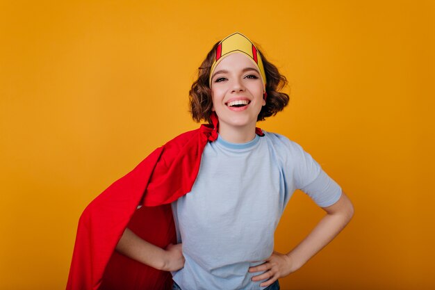 Glimlachende vrouwelijke superheld in speelgoedkroon poseren met plezier