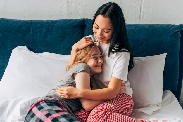 Glimlachende vrouwen die in bed knuffelen