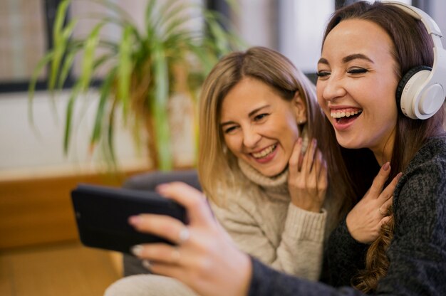 Glimlachende vrouwen die selfie met hoofdtelefoons nemen