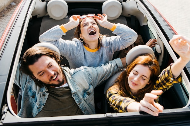 Glimlachende vrouwen en positieve man met plezier in de auto
