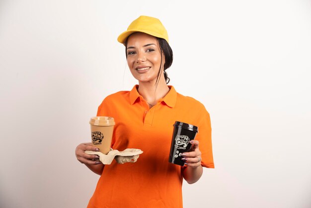 Glimlachende vrouwenkoerier die twee koppen koffie aanbiedt
