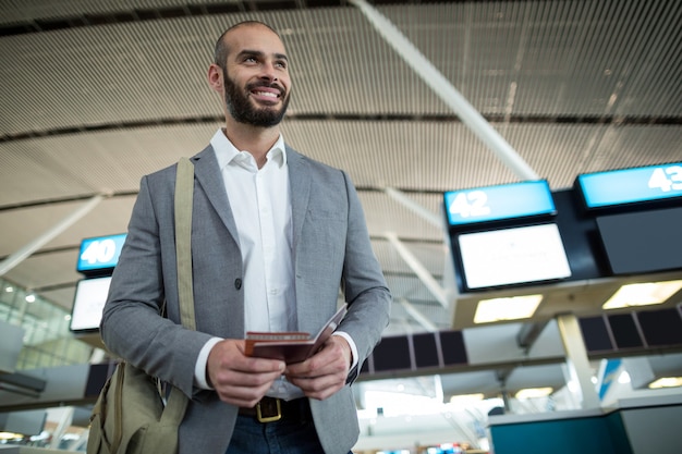Glimlachende zakenman die een instapkaart en een paspoort houdt