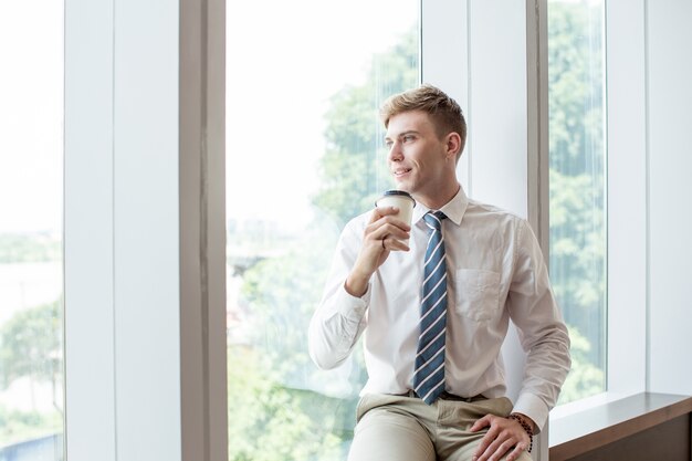 Glimlachende zakenman drinken op vensterbank