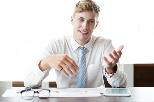Glimlachende zakenman gebaren op kantoor bureau