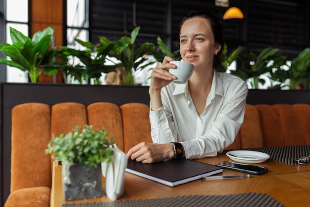 Glimlachende zakenvrouw die koffie drinkt in café en pauze heeft