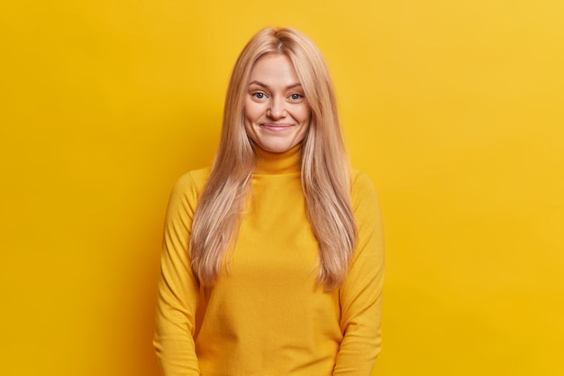 goed uitziende vrouw met blond haar glimlacht aangenaam gekleed in casual coltrui heeft een gezonde huid