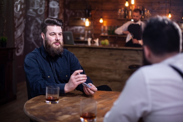 Gratis foto goede oude vrienden die rondhangen met een glas whisky en een kaartspel. stijlvolle mannen. knappe bebaarde mannen.