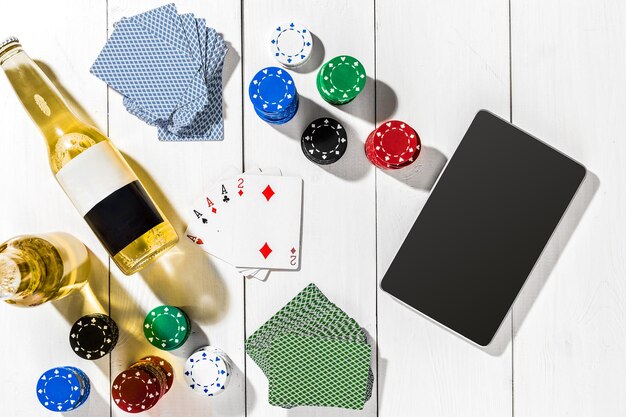Gokken. Pokerfiches, kaarten en de dobbelstenen in de buurt van tablet op witte houten tafel. Bovenaanzicht. Kopieerruimte. Poker. Zomer
