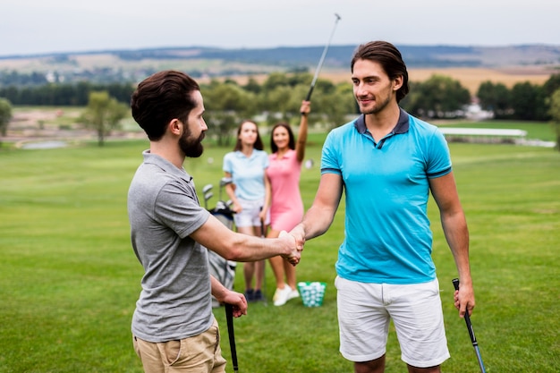 Golfvrienden die handen op golfgebied schudden