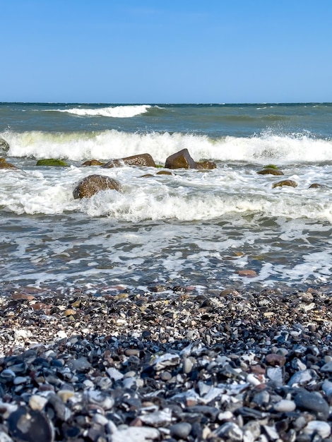 Gratis foto golven in de zee bij de kustlijn op een leeg kiezelstrand