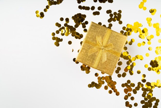 Gouden verpakt geschenk omringd door confetti