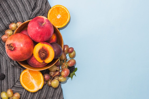 Gratis foto granaatappel; appel; perzik; druiven en gehalveerde citrusvruchten op blauwe achtergrond