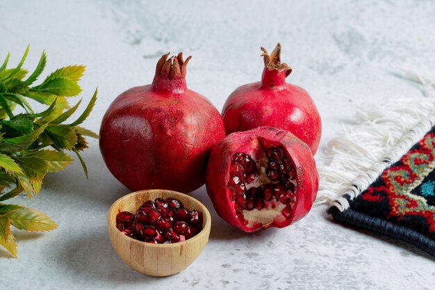 Granaatappelzaden met hele of gesneden granaatappels op grijze muur.