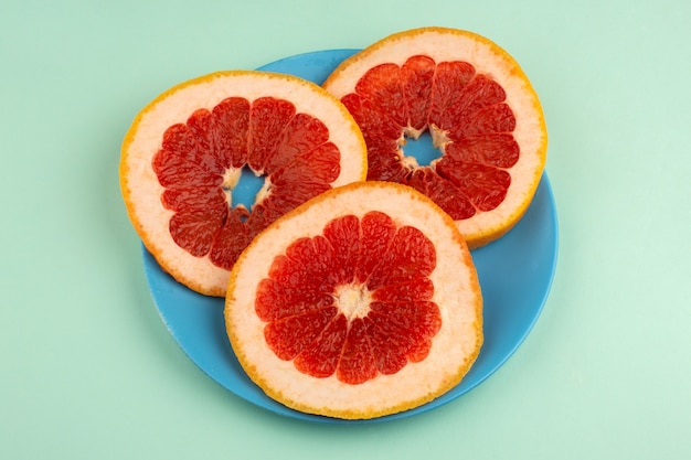 Gratis foto grapefruit ringen verse zachte sappige binnen blauwe plaat en op het ijsblauwe bureau