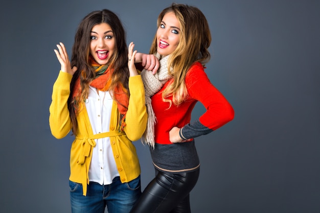 Grappig indoor portret van die hipster meisjes plezier in studio, klassieke kasjmier truien en sjaals dragen