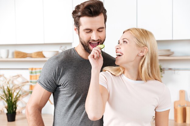 Grappig jong houdend van paar die zich bij keuken en het koken bevinden