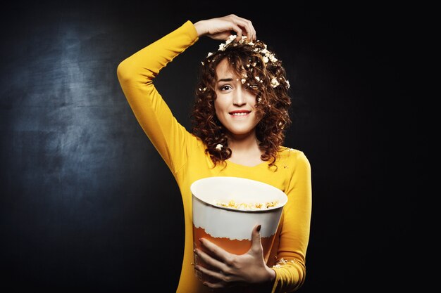 Grappig meisje dat popcorn eet terwijl het letten op shows thuis partij