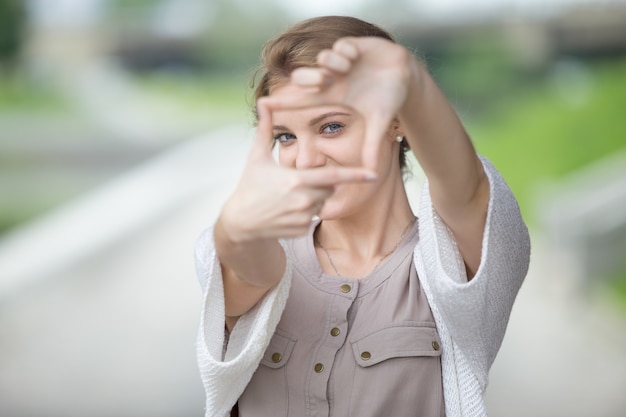 Grappig meisje die een frame met haar handen