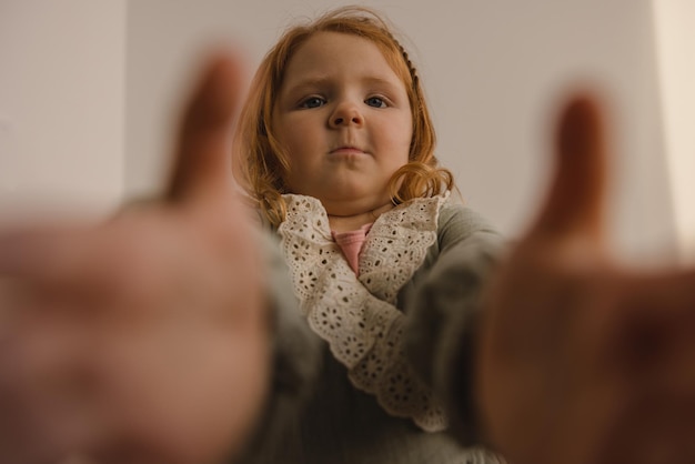 Grappig mollig Kaukasisch meisje met rood haar bereikt voor camera die selfie op witte achtergrond neemt Kinderen concept