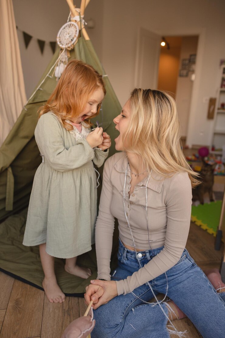 Grappig roodharig klein meisje met jonge blonde vrouw moeder draagt vrijetijdskleding thuis Familieconcept