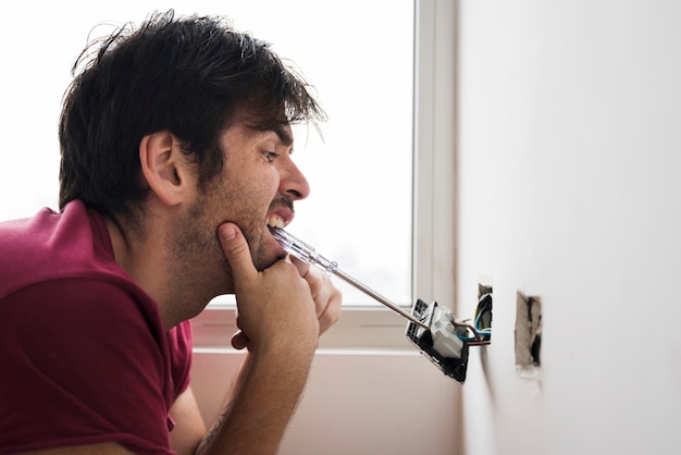 Gratis foto grappige elektricien die stop met schroevedraaier installeren die in mond vervoeren