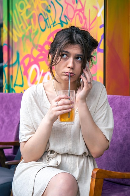 Gratis foto grappige jonge vrouw die aan de telefoon praat met een glas limonade