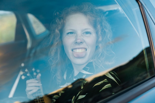 Grappige jonge vrouw die rond in auto voor de gek houden