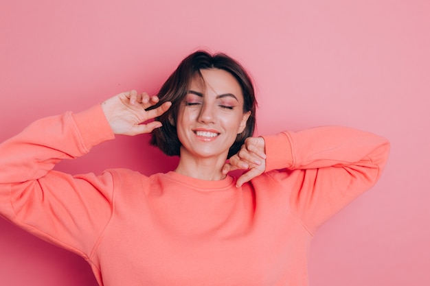 Grappige jonge vrouwen20s in vrijetijdskleding die op roze studioportret wordt geïsoleerd als achtergrond. Mensen emoties levensstijl concept. Hoofd schudden met golvend haar