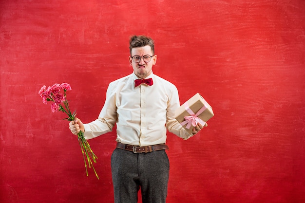 Grappige jongeman met bloemen en cadeau