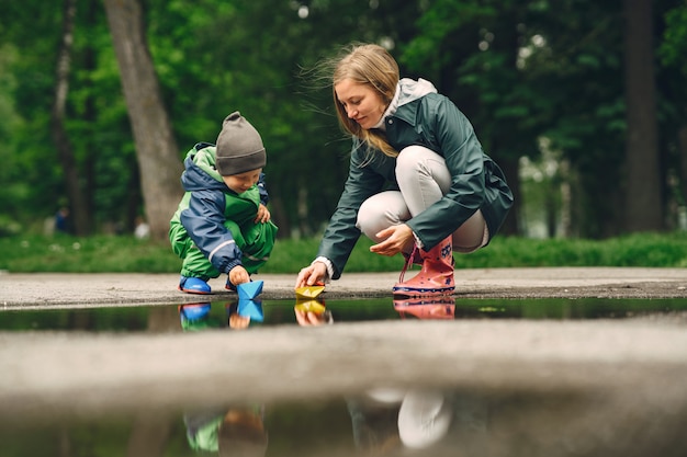 Gratis foto grappige jongen in regenlaarzen spelen in een regenpark