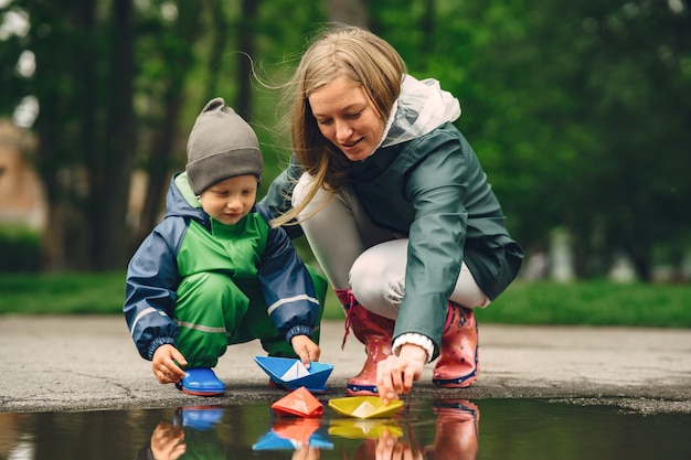 Grappige jongen in regenlaarzen spelen in een regenpark