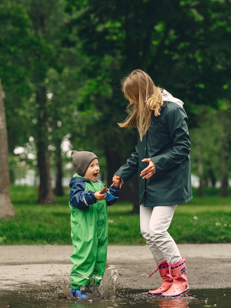 Grappige jongen in regenlaarzen spelen in een regenpark