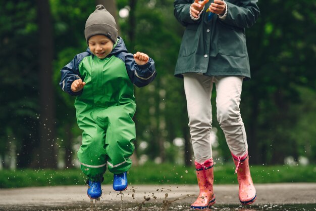 Grappige jongen in regenlaarzen spelen in een regenpark