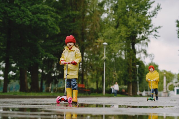 Grappige kinderen in regenlaarzen spelen met schaatsen