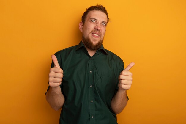 Grappige knappe blonde man thumbs up van twee handen geïsoleerd op oranje muur