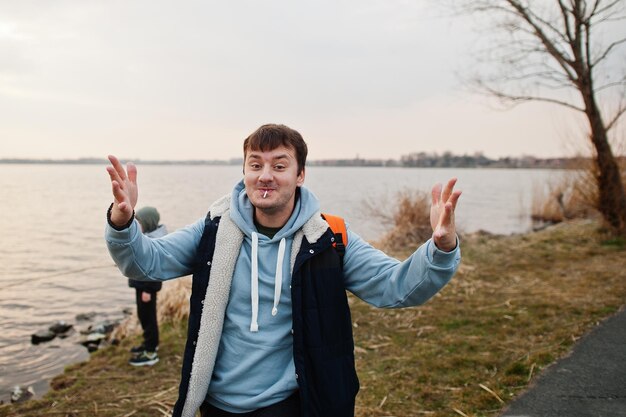 Grappige man in blauwe hoodie met lolly toont verschillende handbewegingen