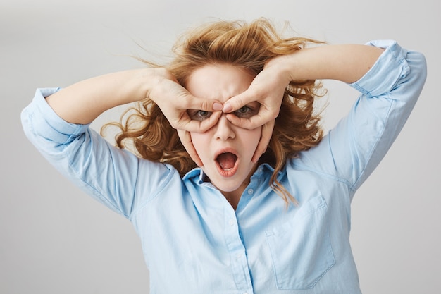 Grappige speelse curly-haired meisje handen masker imiteren superheld maken