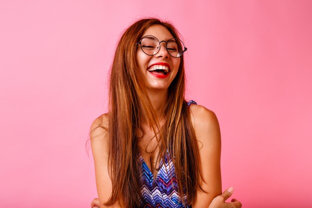 Grappige stijlvolle mooie brunette vrouw met plezier en dansen op roze muur