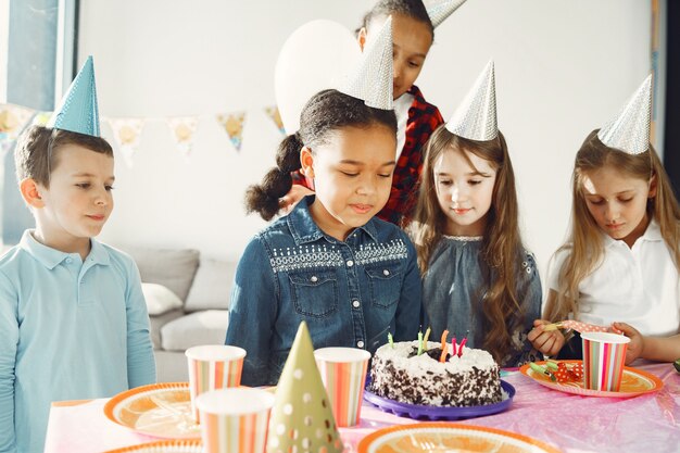 Grappige verjaardagsfeestje voor kinderen in ingerichte kamer. Gelukkige kinderen met cake en ballons.