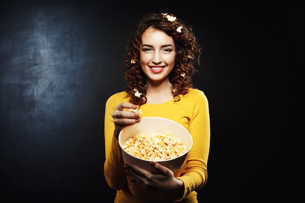 Grappige vrouw met popcorn op en haar dat recht glimlacht kijkt