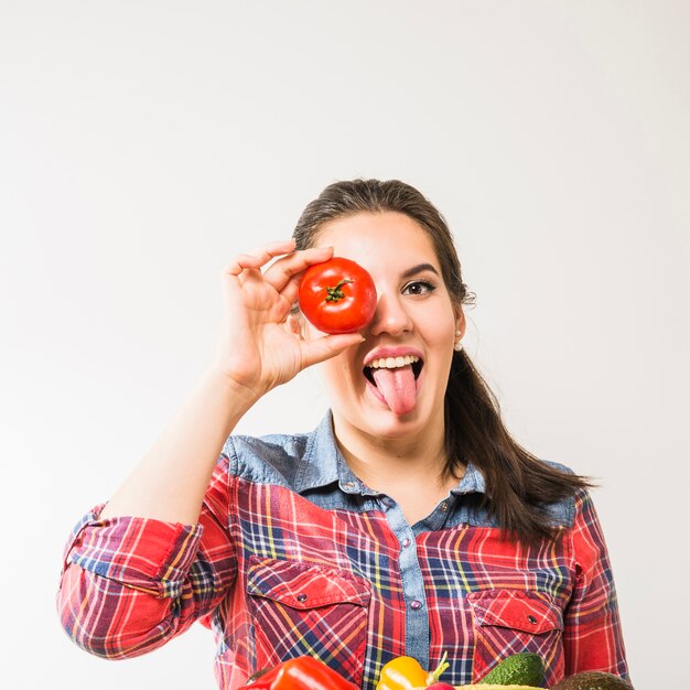 Grappige vrouw met tomaat die tong toont