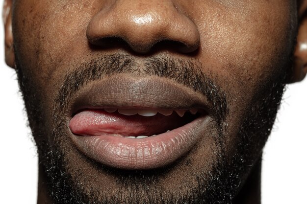 Gremassen. Close-up van het gezicht van de mooie Afro-Amerikaanse jonge man, focus op mond.