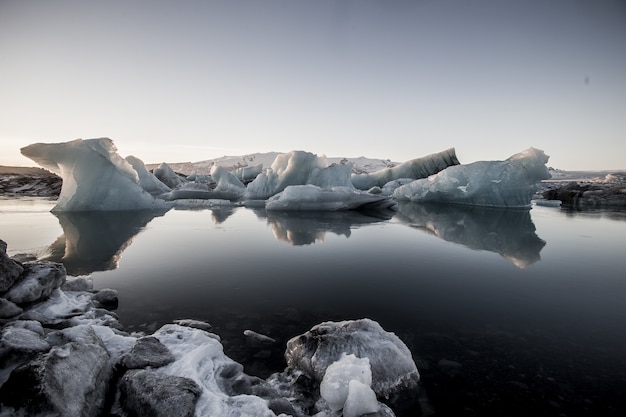 Grijsschaal die van de ijsbergen dichtbij het bevroren water in besneeuwde Jokulsarlon, IJsland wordt geschoten