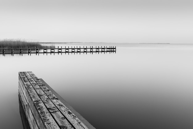 Grijstinten shot van een houten pier in de buurt van de zee overdag